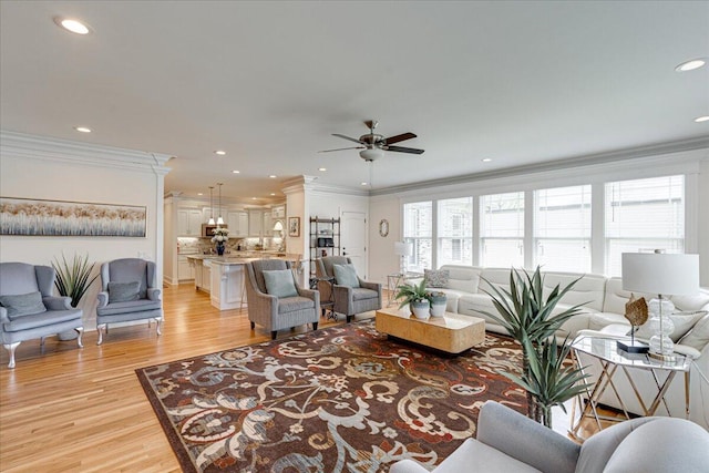 living room featuring light hardwood / wood-style flooring, ceiling fan, and ornamental molding