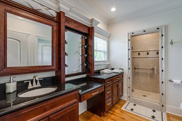 bathroom with vanity, a shower with door, wood-type flooring, and ornamental molding