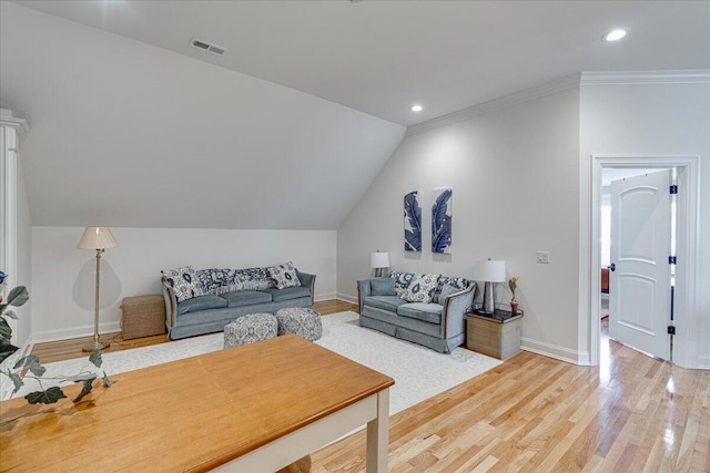 living room featuring wood-type flooring, ornamental molding, and vaulted ceiling