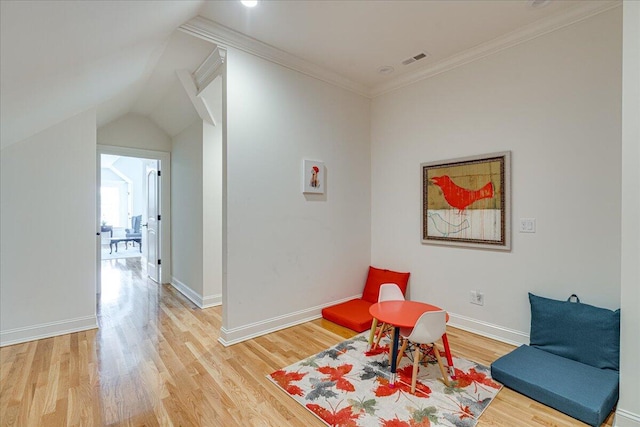 living area featuring hardwood / wood-style floors, lofted ceiling, and crown molding