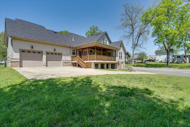 back of house featuring a yard, a garage, and a sunroom