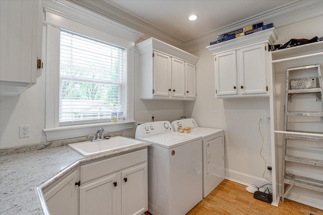 washroom featuring cabinets, ornamental molding, sink, washer and dryer, and light hardwood / wood-style floors