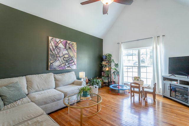 living room with ceiling fan, high vaulted ceiling, and light hardwood / wood-style flooring