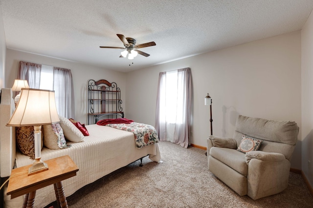 bedroom with a textured ceiling, carpet floors, ceiling fan, and multiple windows