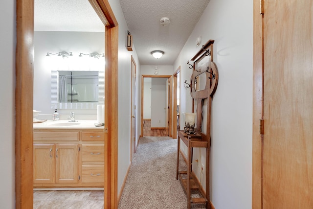 corridor featuring a textured ceiling, light carpet, and sink