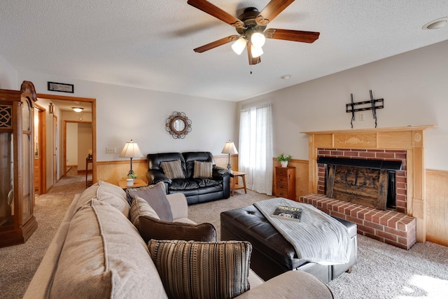 carpeted living room with a brick fireplace, wood walls, ceiling fan, and a textured ceiling