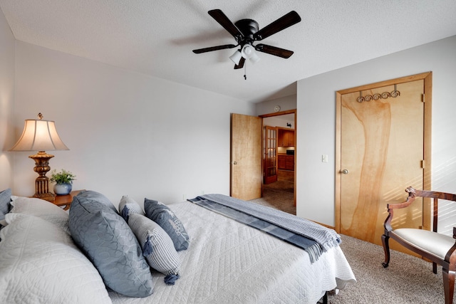 carpeted bedroom with ceiling fan and a textured ceiling