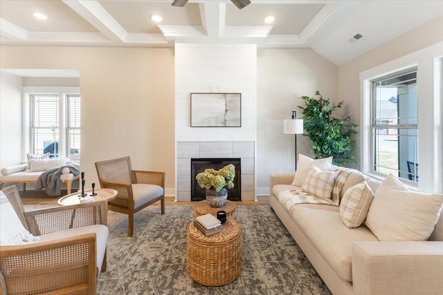 living room with hardwood / wood-style flooring, a tile fireplace, coffered ceiling, and beam ceiling