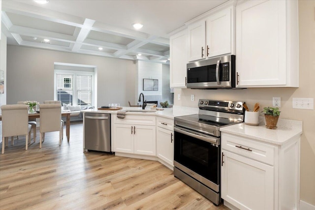 kitchen featuring stainless steel appliances, sink, coffered ceiling, beamed ceiling, and white cabinetry