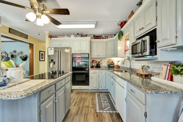 kitchen featuring light hardwood / wood-style floors, black appliances, sink, backsplash, and white cabinetry