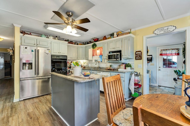 kitchen featuring stainless steel appliances, a center island, crown molding, backsplash, and light wood-type flooring