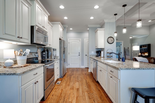 kitchen featuring appliances with stainless steel finishes, sink, decorative light fixtures, light hardwood / wood-style flooring, and white cabinetry