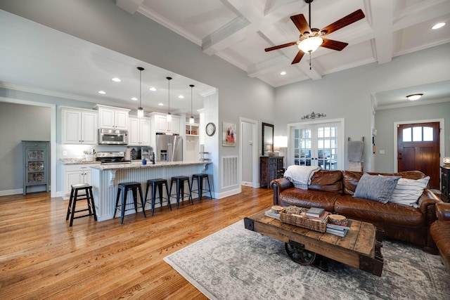 living room featuring beamed ceiling, ornamental molding, coffered ceiling, and light wood-type flooring