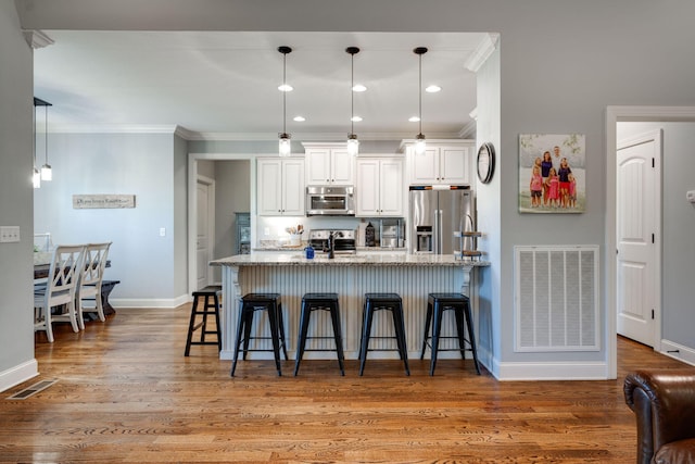 kitchen featuring a breakfast bar area, light stone countertops, light wood-type flooring, and appliances with stainless steel finishes