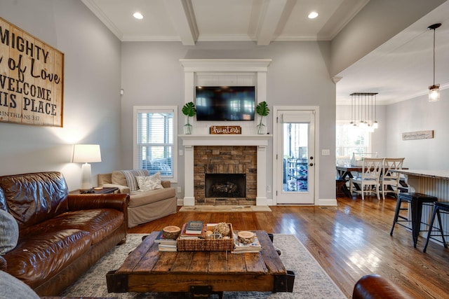 living room with beam ceiling, a fireplace, a healthy amount of sunlight, and hardwood / wood-style flooring