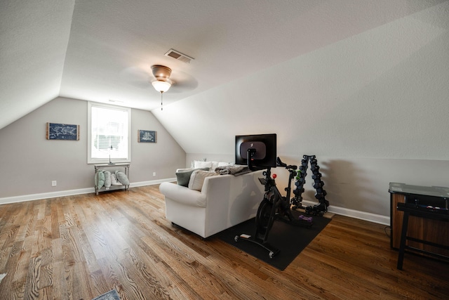 interior space featuring lofted ceiling, ceiling fan, wood-type flooring, and a textured ceiling