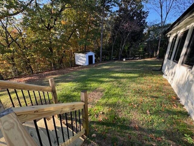 view of yard featuring a wooden deck and a storage shed