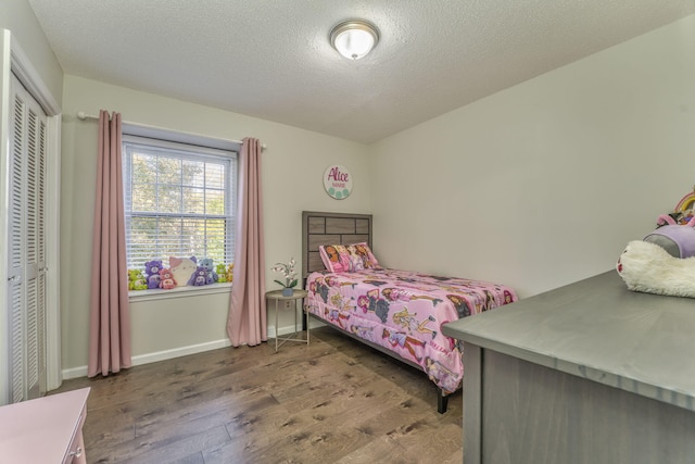 bedroom featuring dark hardwood / wood-style flooring, a textured ceiling, and a closet