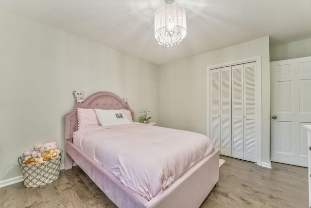 bedroom with a closet, a chandelier, a textured ceiling, and light hardwood / wood-style flooring