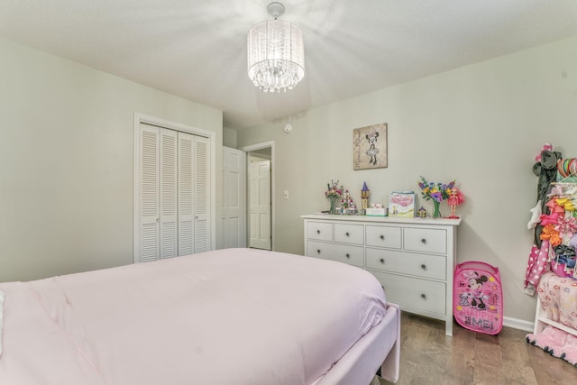 bedroom featuring light wood-type flooring, a textured ceiling, a closet, and an inviting chandelier