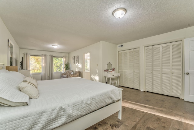 bedroom featuring multiple closets, hardwood / wood-style floors, and a textured ceiling