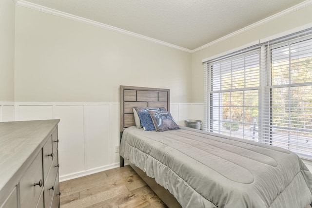 bedroom featuring multiple windows, light hardwood / wood-style flooring, crown molding, and a textured ceiling