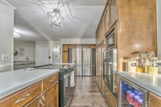 kitchen featuring stainless steel appliances, light hardwood / wood-style floors, a textured ceiling, and wine cooler