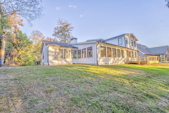 back of property featuring a deck, a lawn, and a sunroom