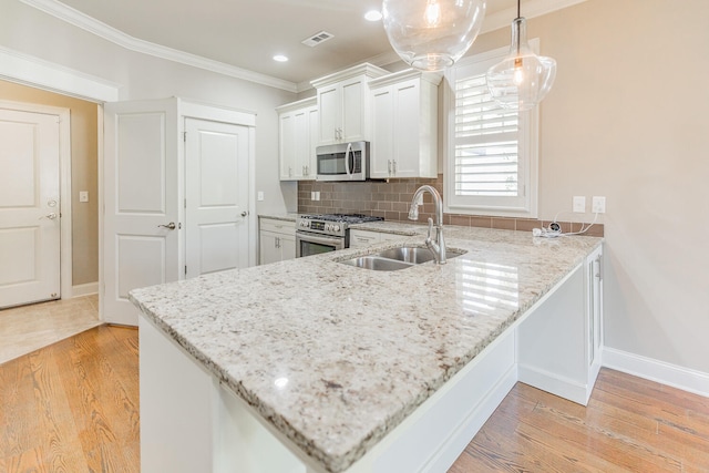 kitchen featuring appliances with stainless steel finishes, light hardwood / wood-style floors, white cabinetry, and sink