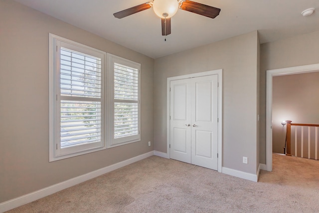 unfurnished bedroom with ceiling fan, light carpet, and a closet