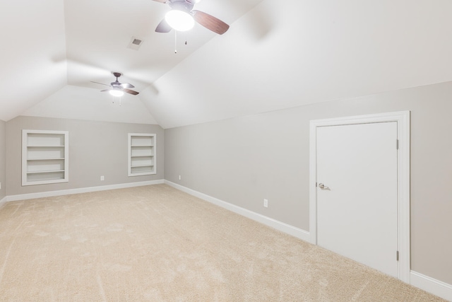 additional living space featuring built in shelves, ceiling fan, light colored carpet, and lofted ceiling