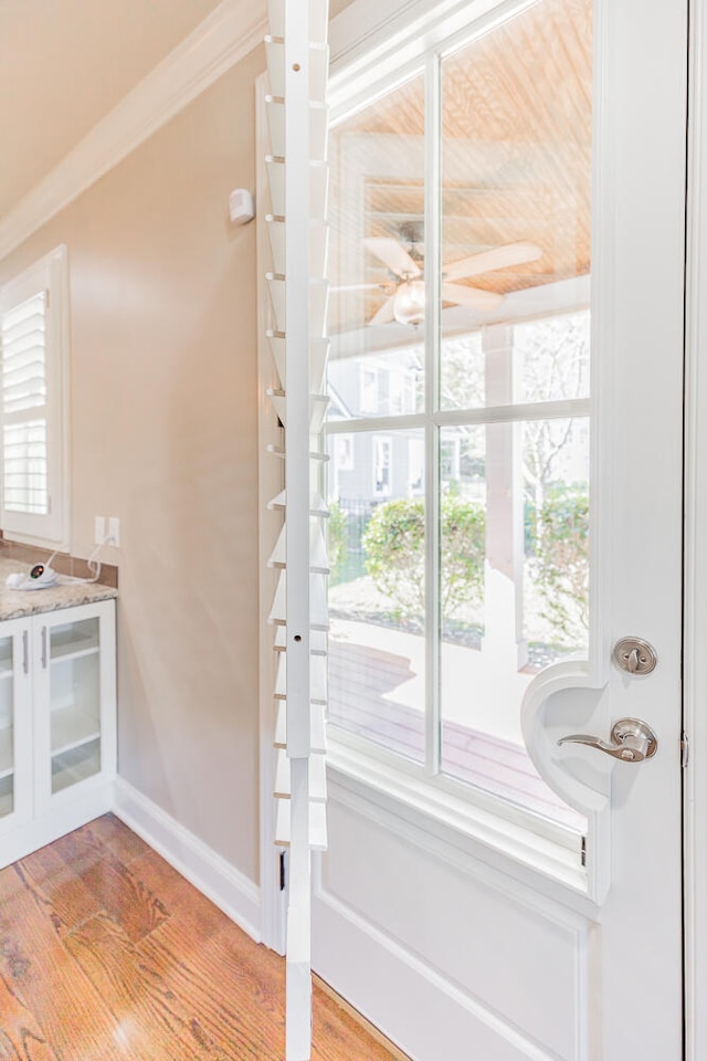 entryway featuring crown molding, plenty of natural light, and light wood-type flooring