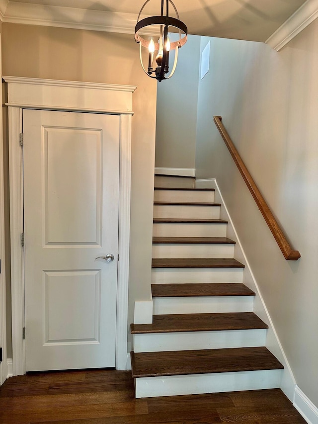 stairway featuring an inviting chandelier, ornamental molding, baseboards, and wood finished floors