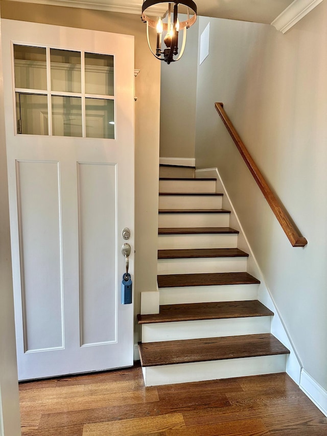 stairs featuring wood finished floors and a chandelier