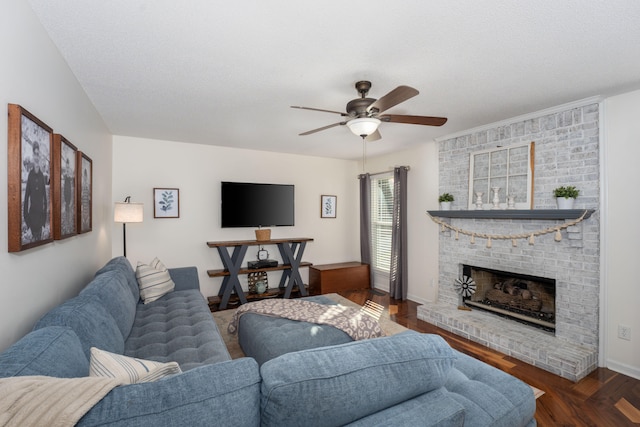 living room with a textured ceiling, a brick fireplace, ceiling fan, and dark wood-type flooring