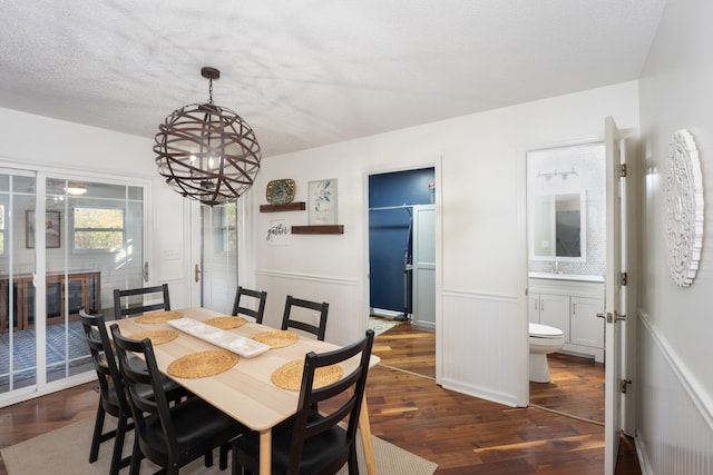 dining room featuring dark hardwood / wood-style flooring, a textured ceiling, and an inviting chandelier