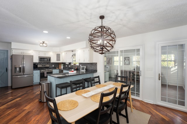 dining space featuring a chandelier, a textured ceiling, dark hardwood / wood-style floors, and sink