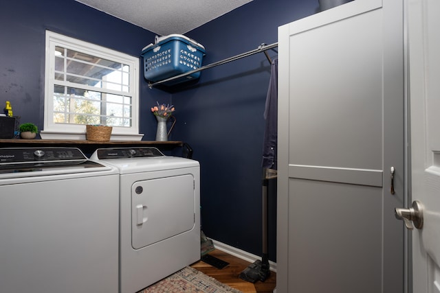 clothes washing area featuring washing machine and clothes dryer, wood-type flooring, and a textured ceiling