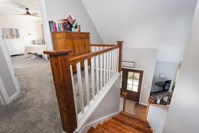 staircase featuring ceiling fan, wood-type flooring, and lofted ceiling