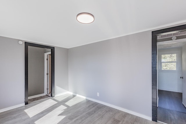 empty room with ornamental molding and light wood-type flooring