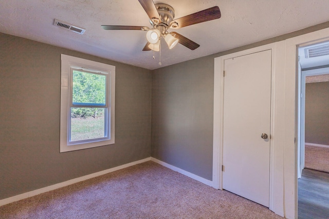 unfurnished bedroom featuring ceiling fan, a textured ceiling, and light carpet