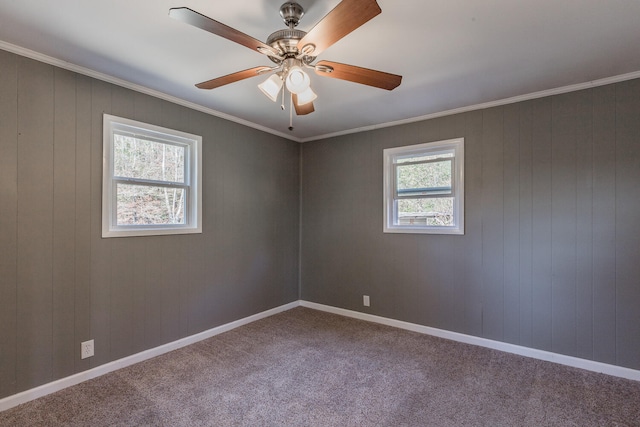 carpeted empty room with wooden walls, ceiling fan, and crown molding