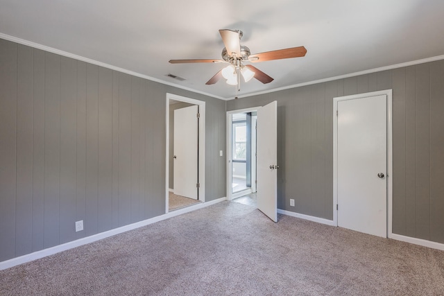 empty room with wood walls, light carpet, and ceiling fan