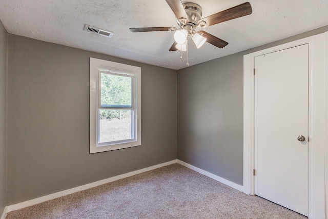 unfurnished bedroom with ceiling fan, a textured ceiling, and light carpet