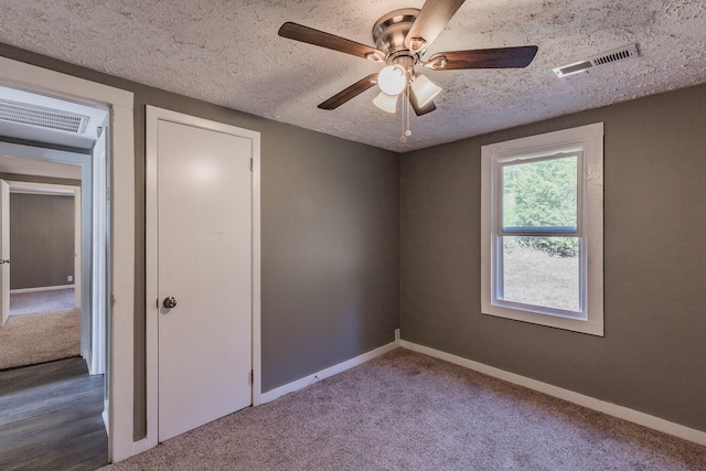 carpeted spare room with a textured ceiling and ceiling fan