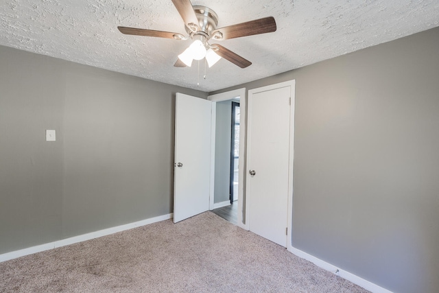 unfurnished bedroom featuring carpet, a textured ceiling, and ceiling fan