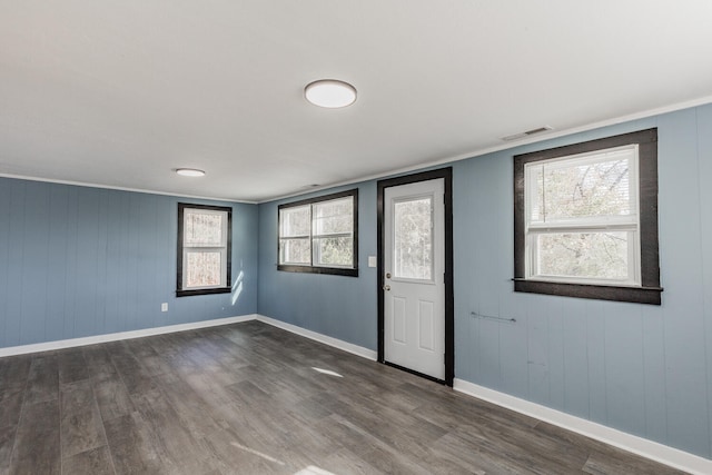 interior space with wood walls, dark hardwood / wood-style floors, and crown molding