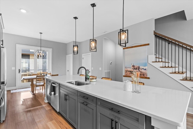 kitchen with sink, pendant lighting, light hardwood / wood-style floors, gray cabinets, and appliances with stainless steel finishes