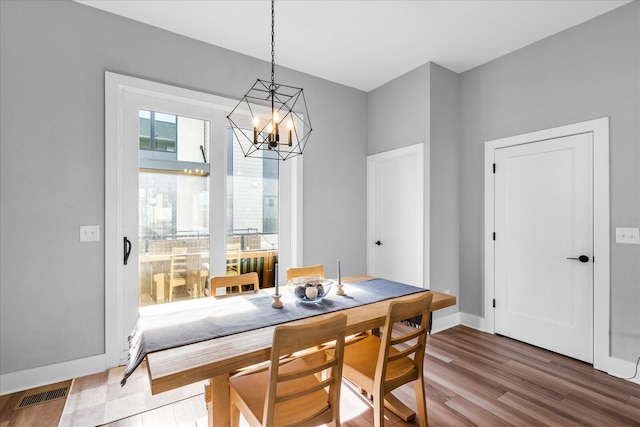 dining space with hardwood / wood-style floors and a notable chandelier