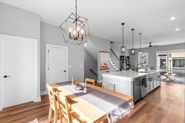 dining area with ceiling fan with notable chandelier, dark hardwood / wood-style flooring, and sink